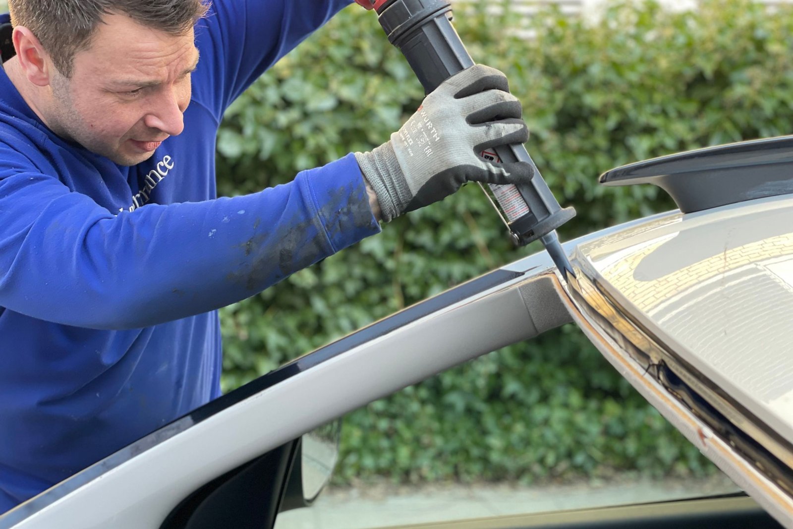 Technicien Carglass installant un pare-brise neuf sur une voiture dans un atelier lumineux